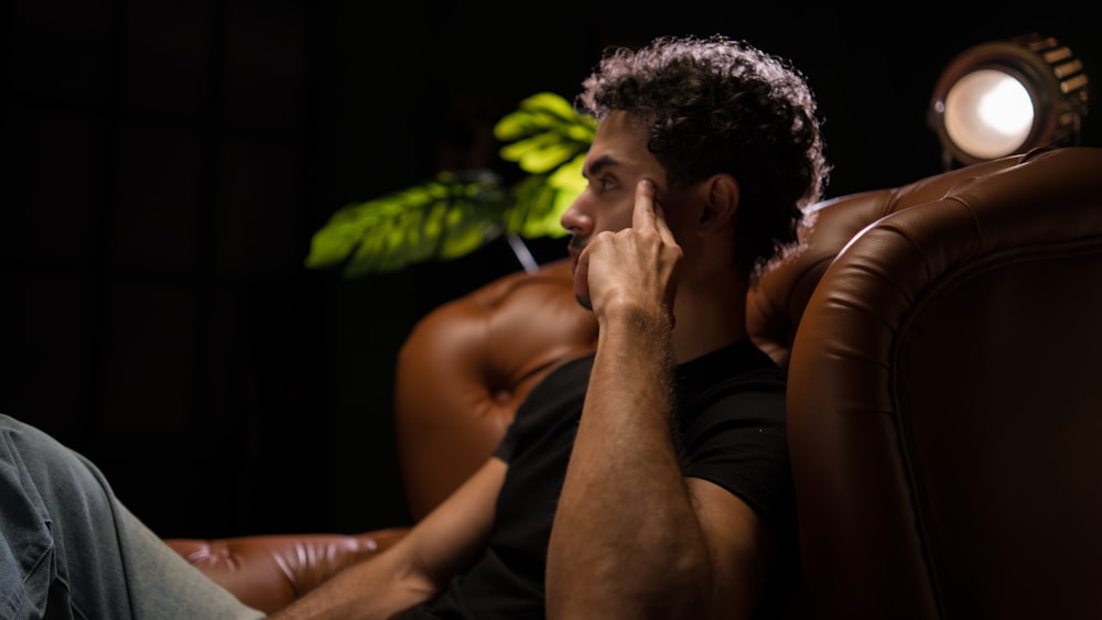 a man sitting in a chair with his hand on his face