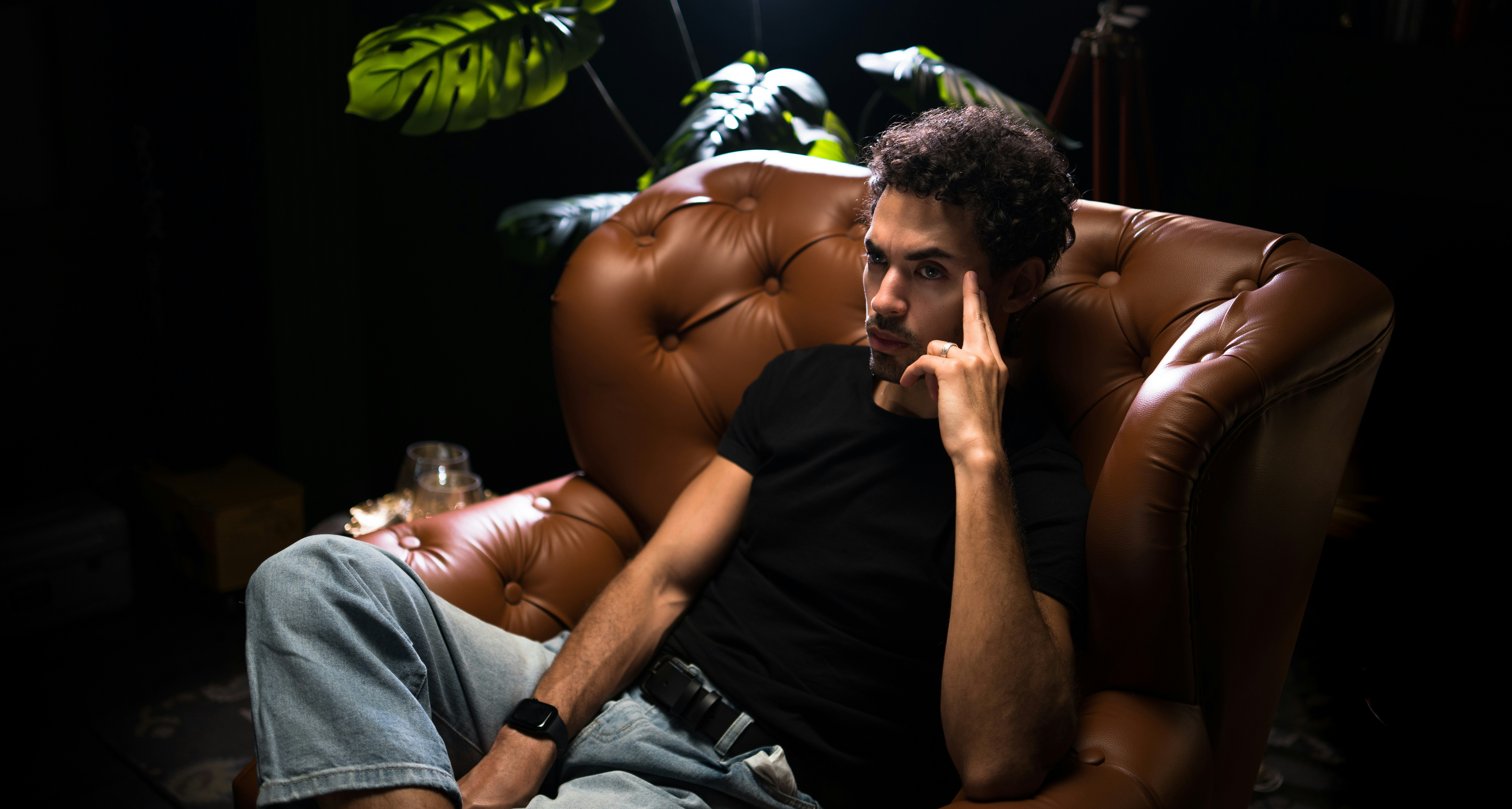 a man sitting in a brown chair talking on a cell phone