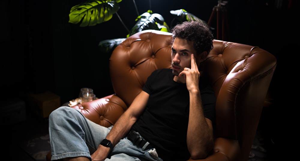 a man sitting in a brown chair talking on a cell phone