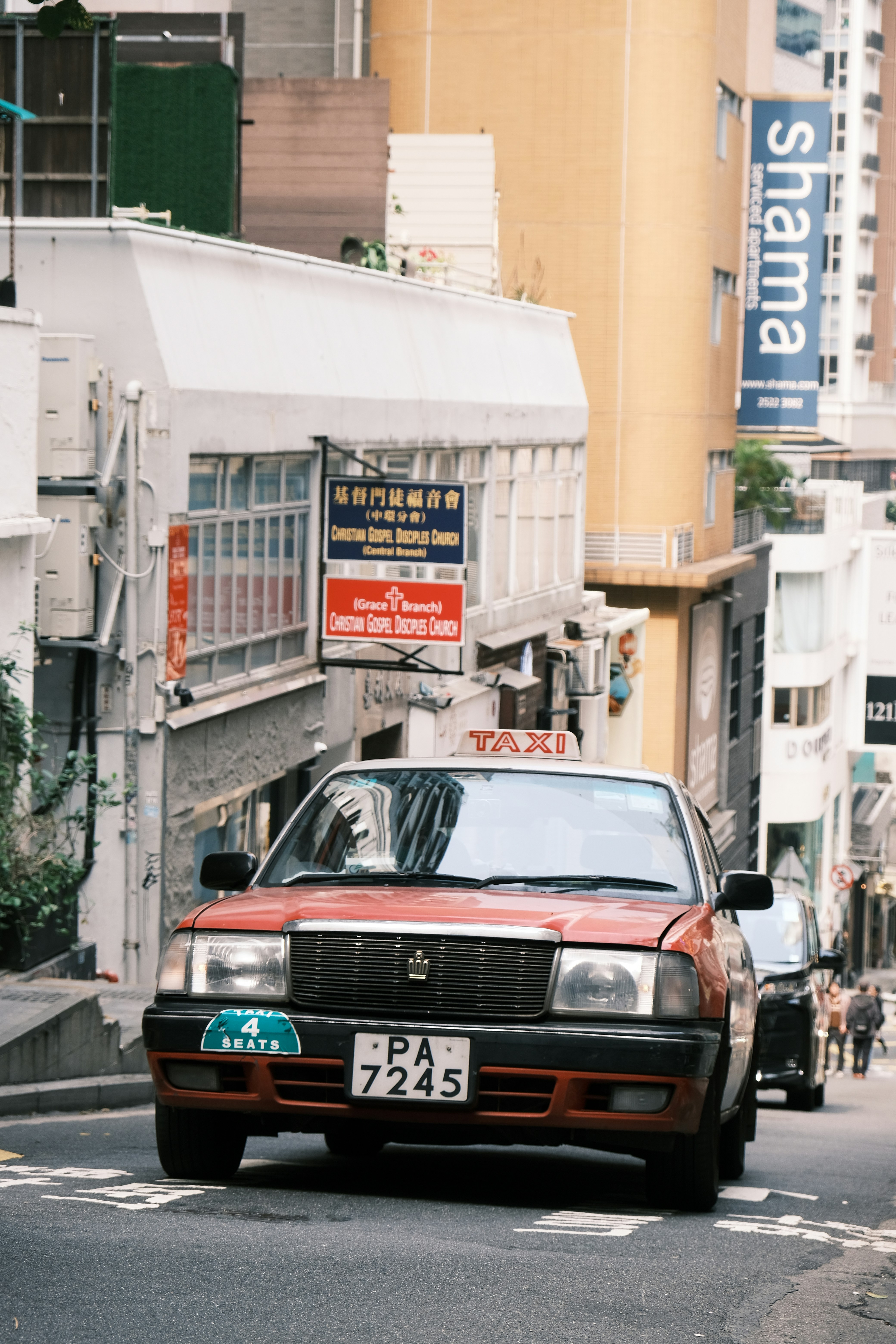 A red car driving down a street next to tall buildings photo – Free 홍콩 ...