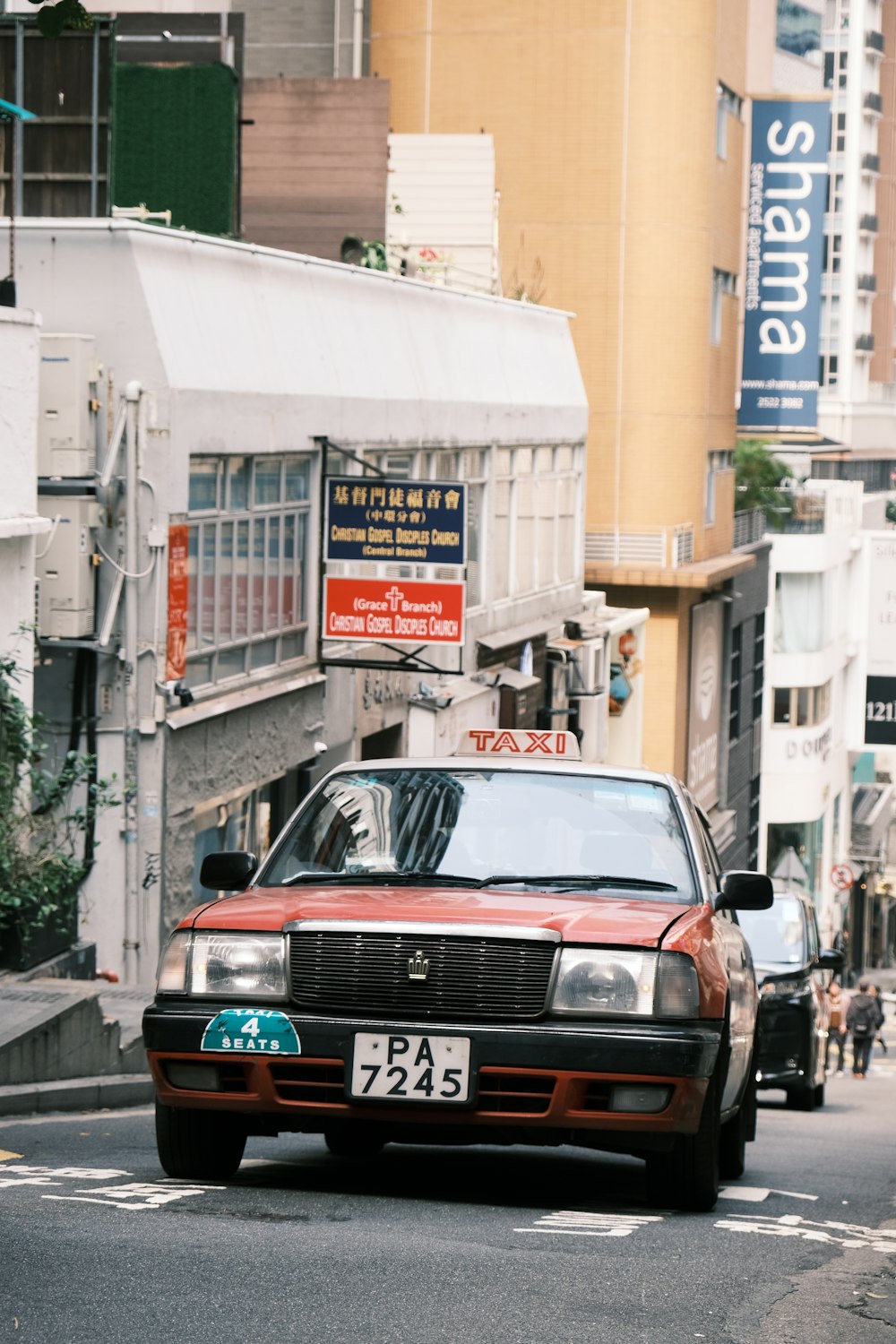 a red car driving down a street next to tall buildings