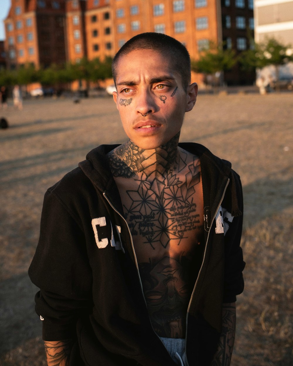 a man with tattoos on his chest standing in front of a building