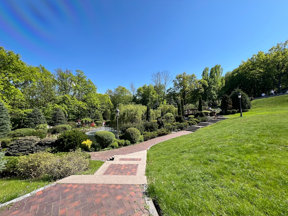 a brick walkway leads to a lush green park