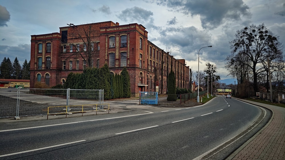 an empty street in front of a large brick building