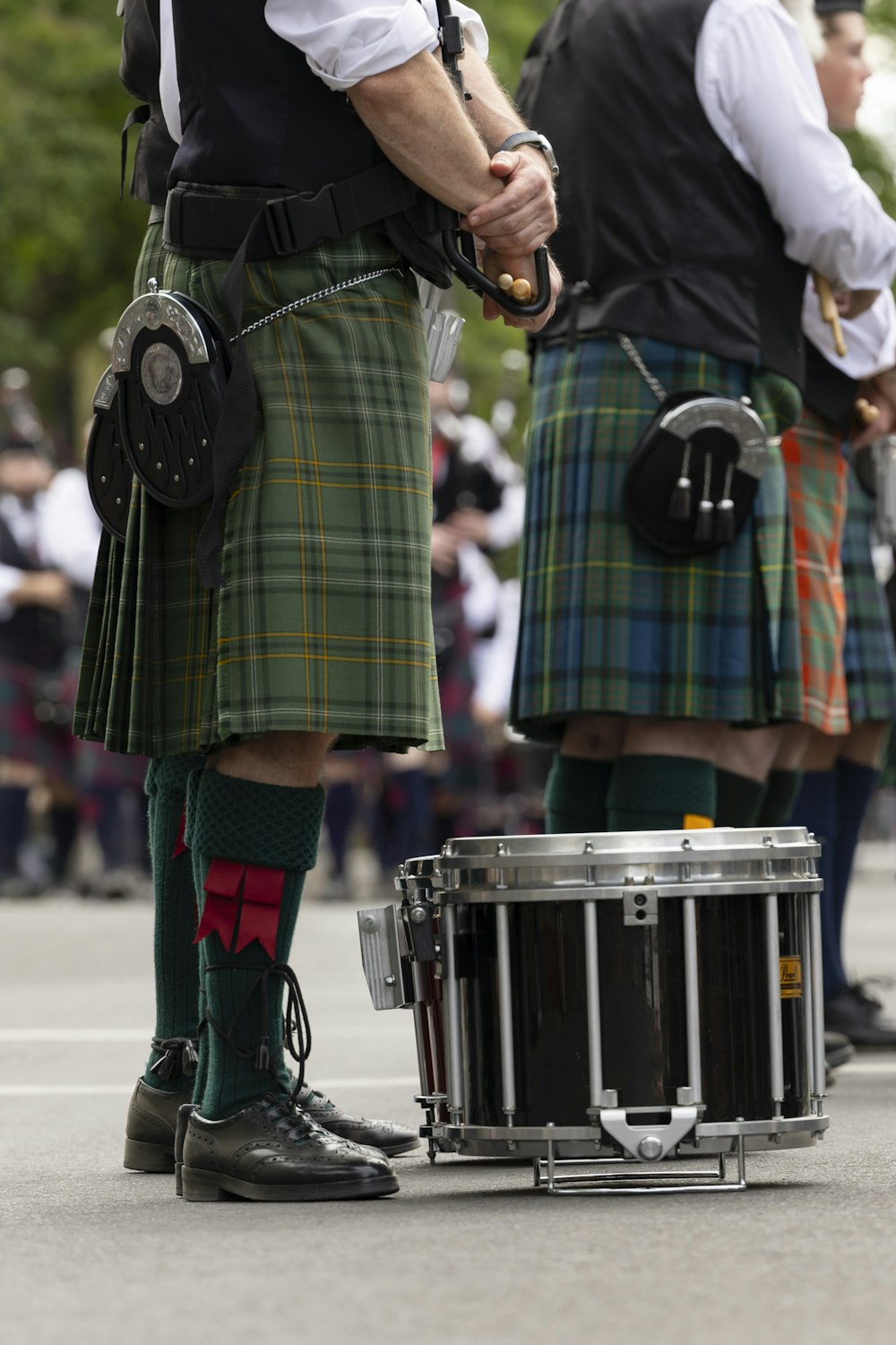 a group of men in kilts standing next to a drum