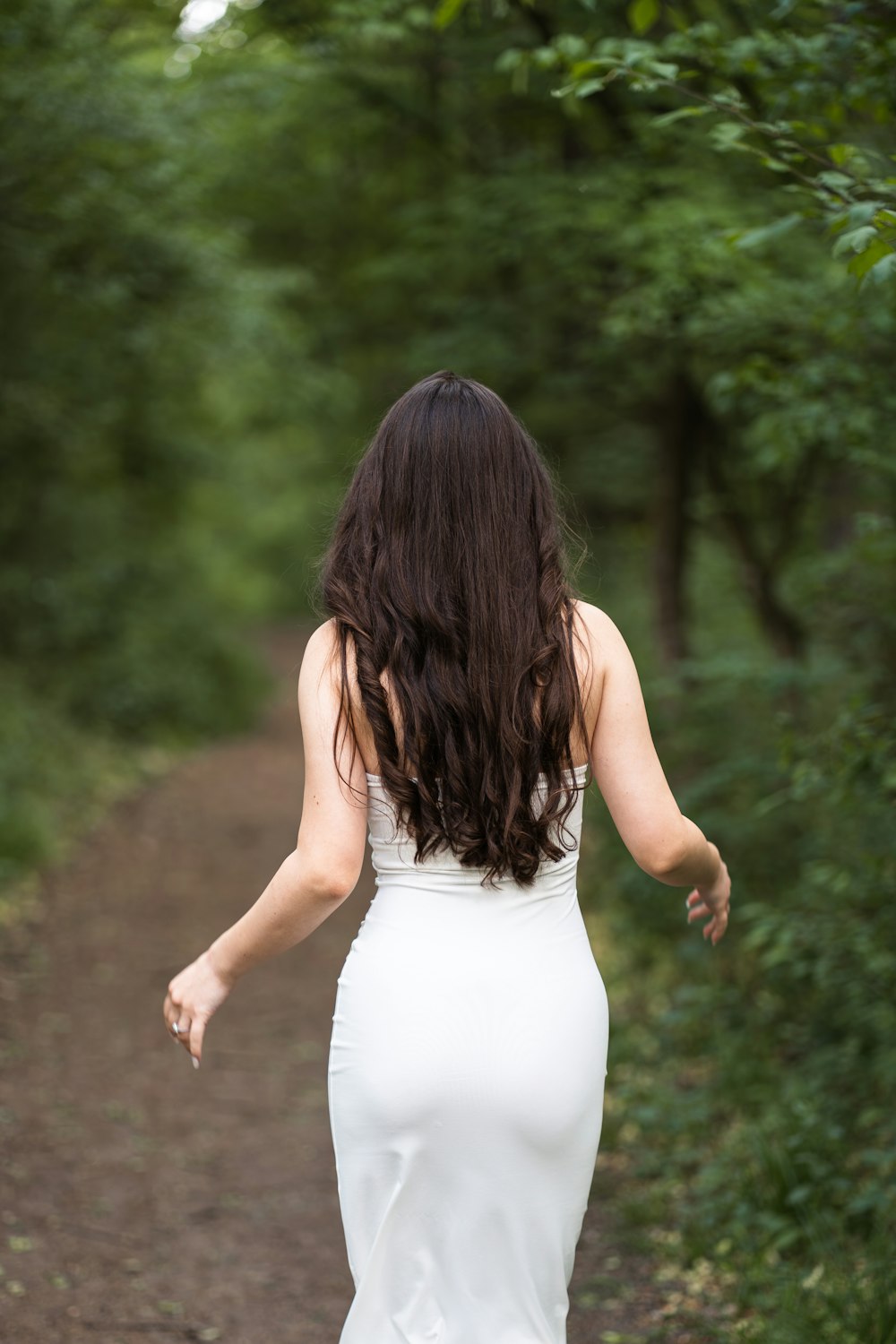 a woman in a white dress walking down a path