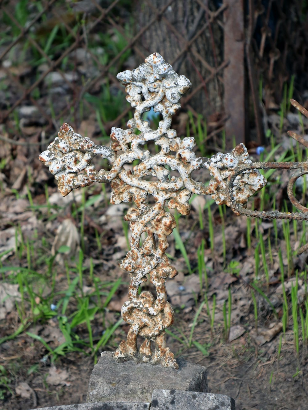 a rusty iron cross sitting on top of a rock