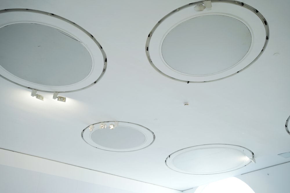 a white room with four round mirrors on the ceiling