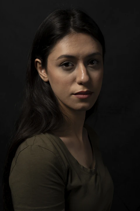 Rembrandt portrait lighting on a woman in green shirt with the signature triangular highlight