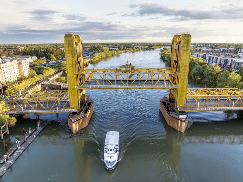 a boat is going under a yellow bridge