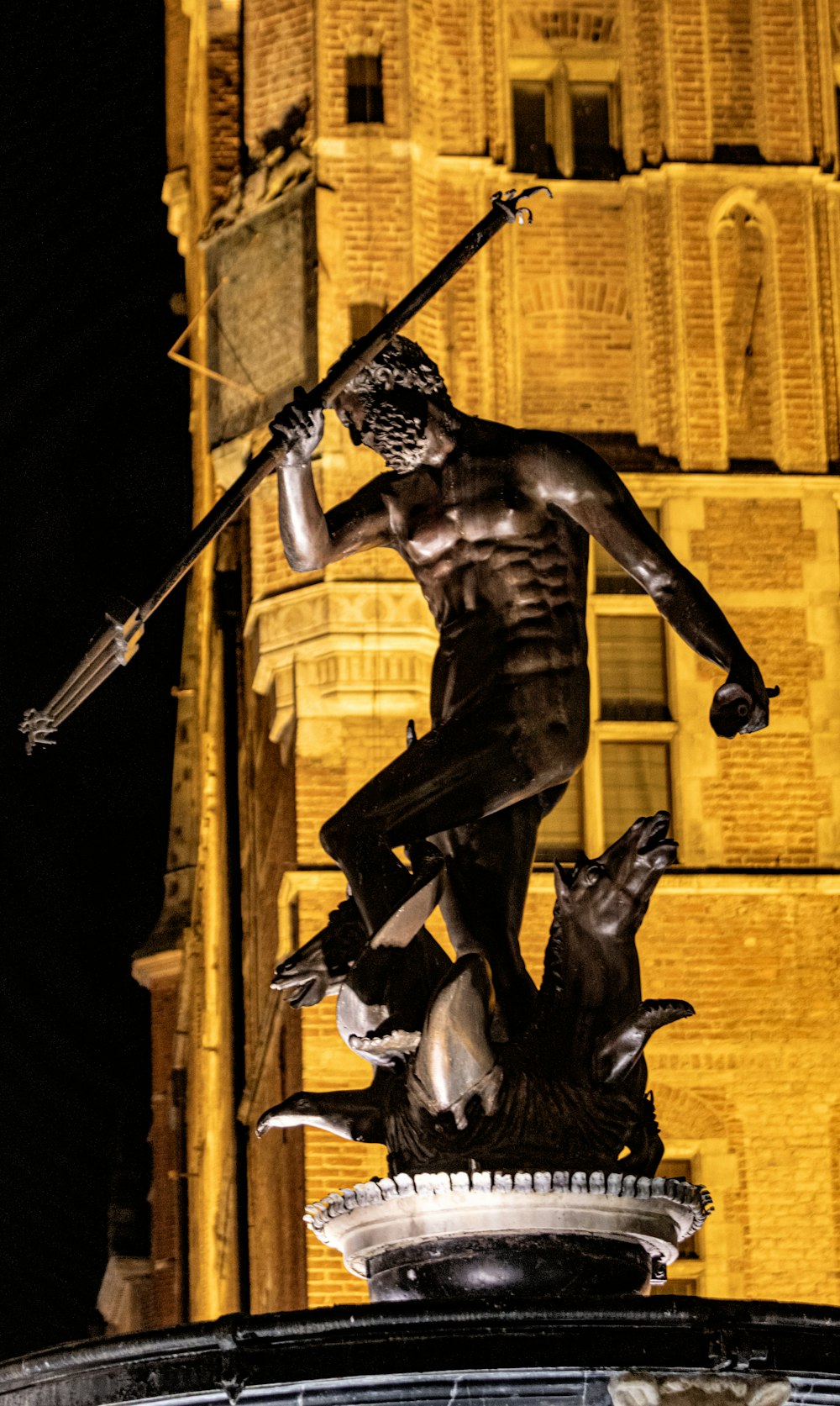 uma estátua de um homem segurando uma espada em cima de uma fonte