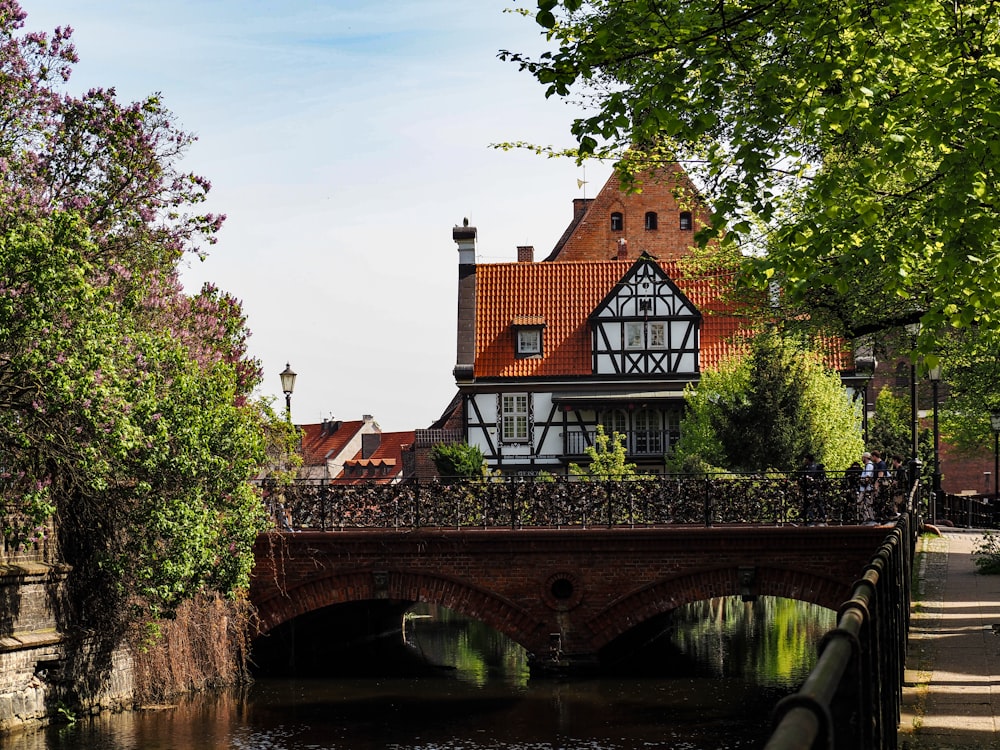 a bridge over a river with a house in the background