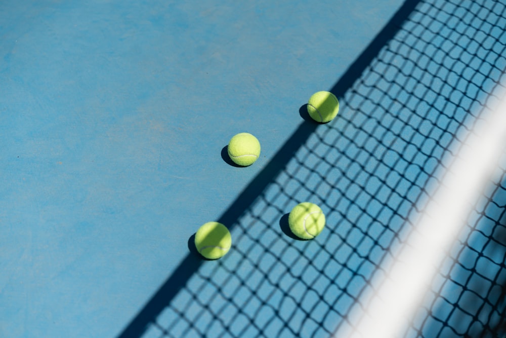 four tennis balls on a blue tennis court