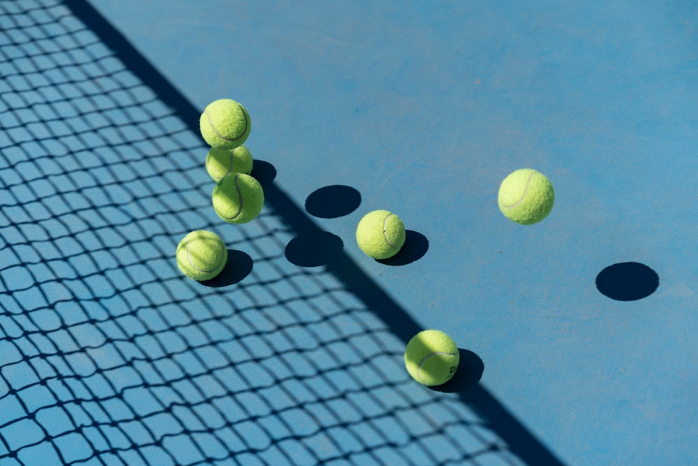 several tennis balls on a blue tennis court