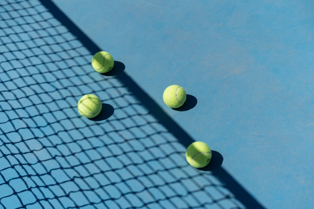 three tennis balls on a blue tennis court