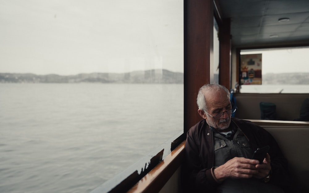 um homem sentado em um barco olhando para seu celular