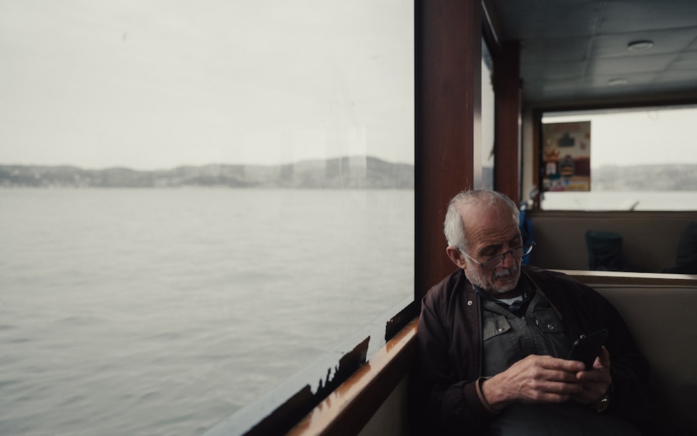 a man sitting on a boat looking at his cell phone