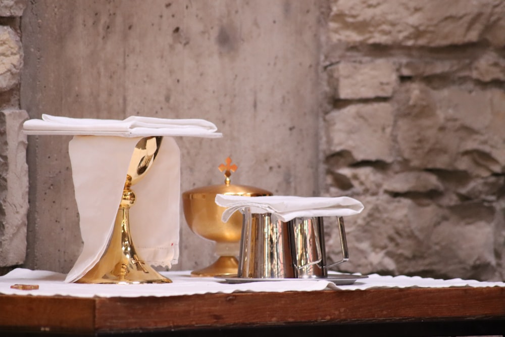a table topped with a gold plate and a silver cup