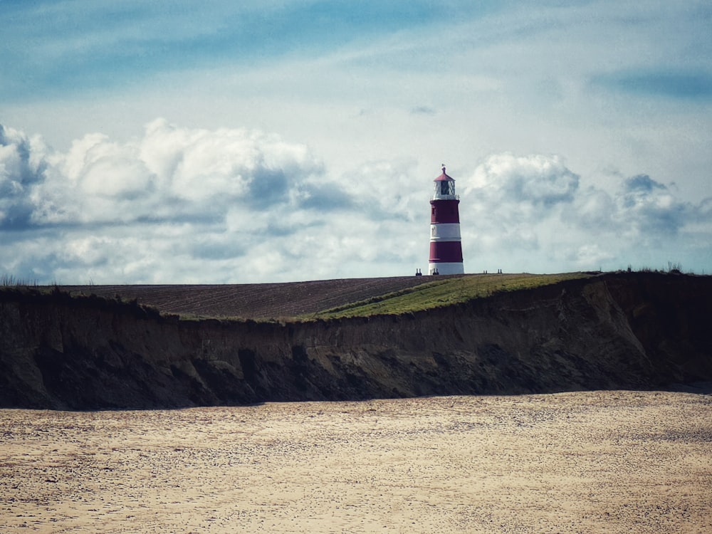 a lighthouse on top of a cliff on a beach