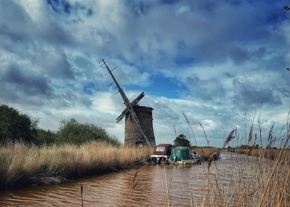 a truck driving down a flooded road next to a windmill