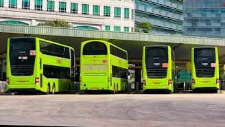 a row of green double decker buses parked next to each other
