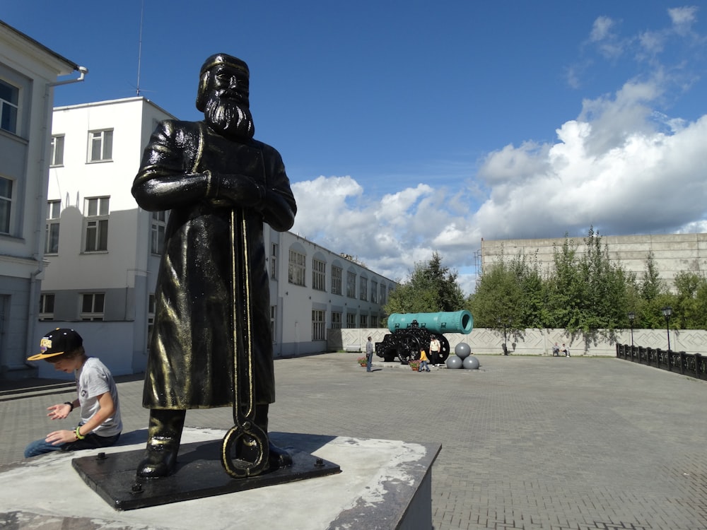 a man kneeling down next to a statue of a man