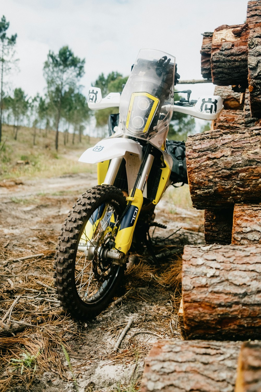 a dirt bike parked next to a pile of logs