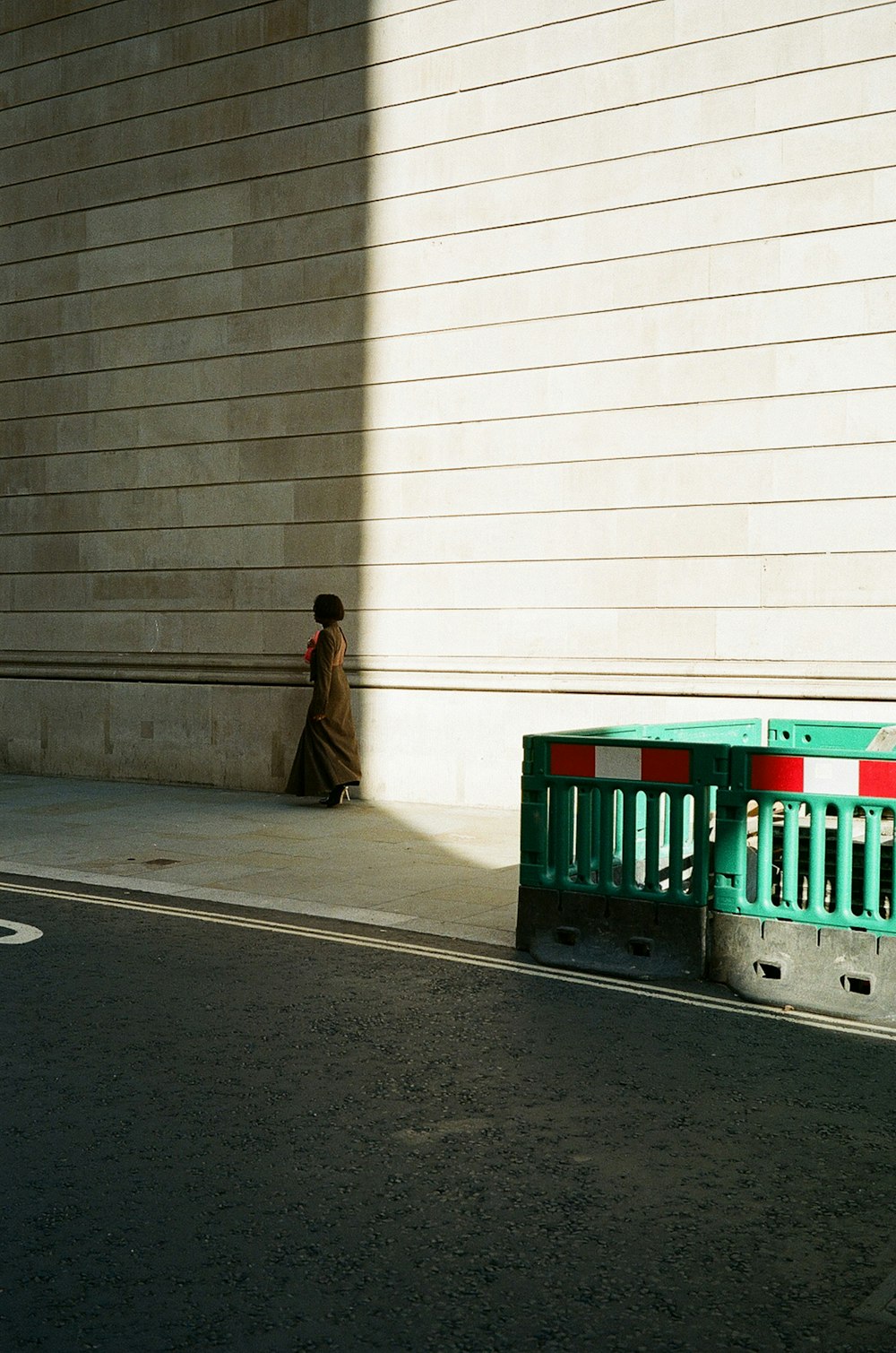 a woman walking down a street next to a building