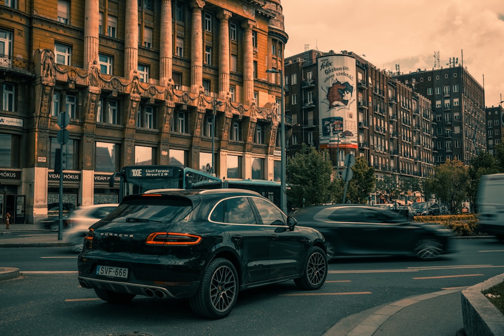 a black car driving down a street next to tall buildings