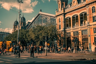 a group of people walking across a street next to tall buildings