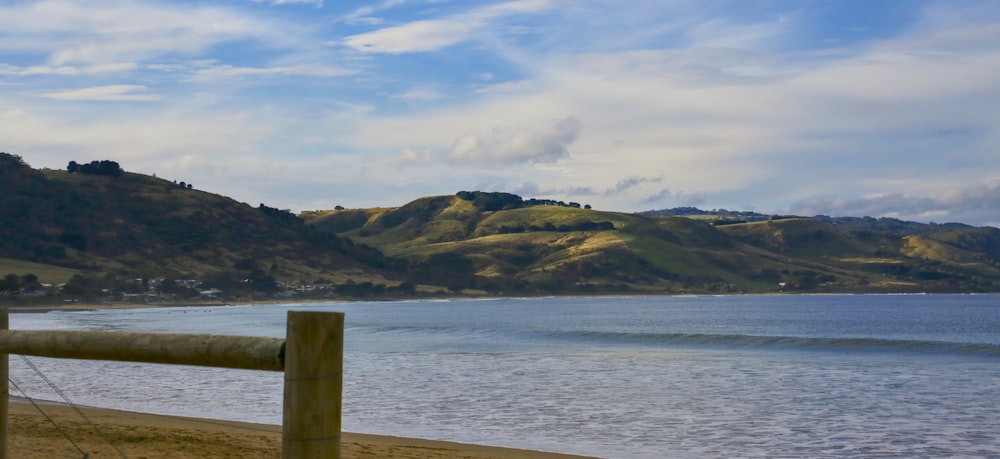 a wooden fence on a beach next to a body of water