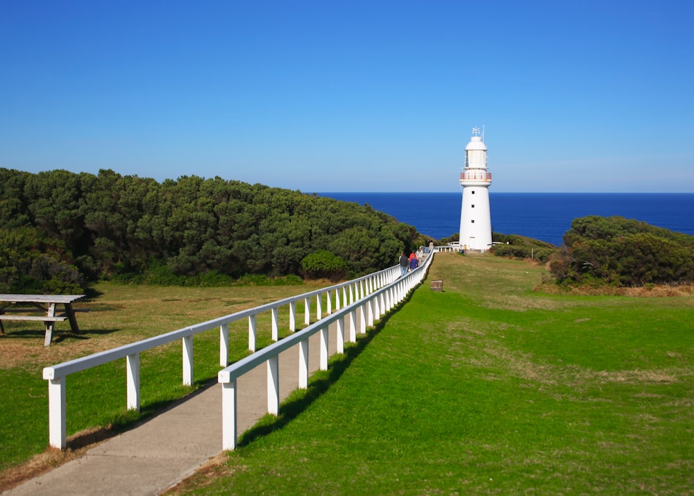 a white light house sitting on top of a lush green field