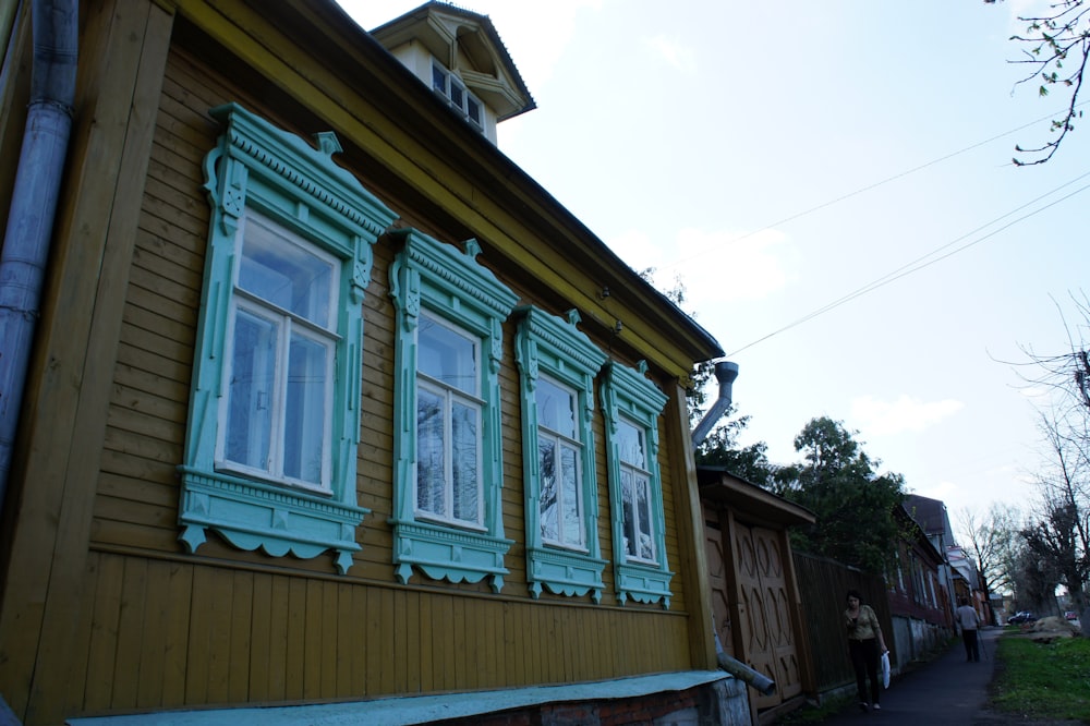 ein gelbes Haus mit grünen Zierleisten und Fenstern