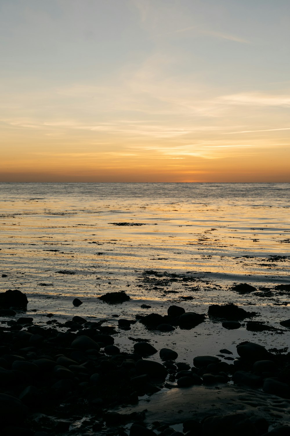 Le soleil se couche sur l’océan avec des rochers au premier plan