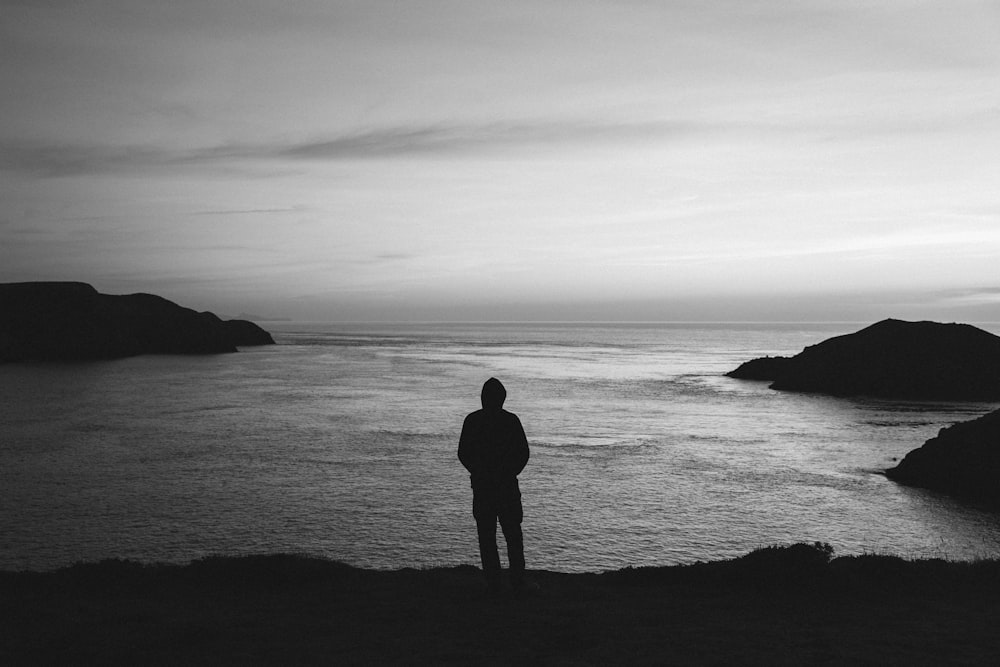 una persona in piedi sulla cima di una collina vicino all'oceano