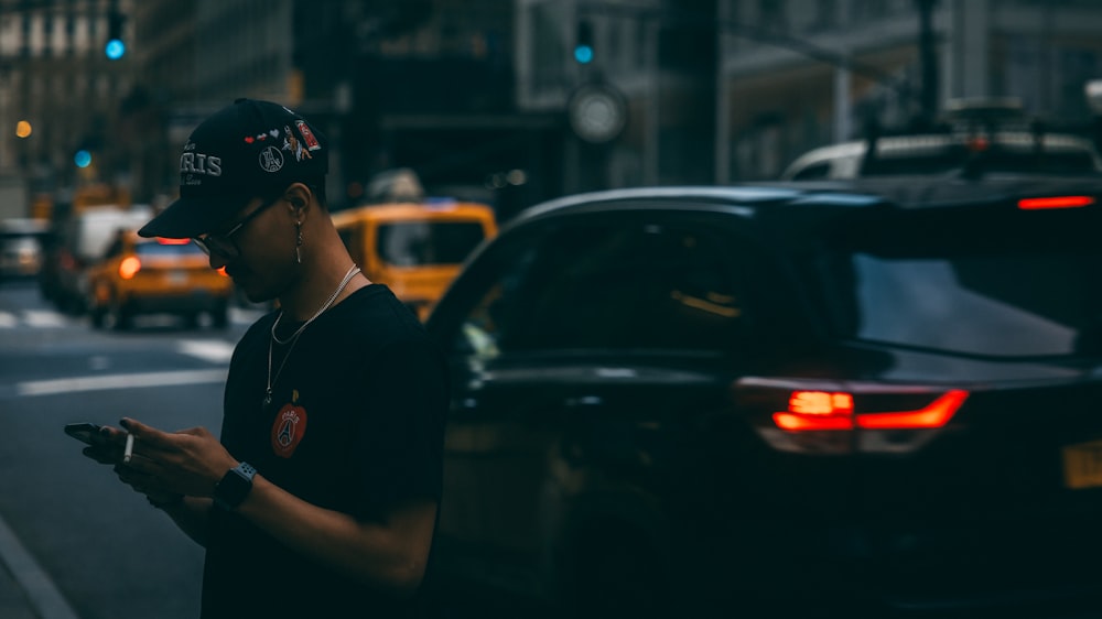 a man standing on the side of a street holding a cell phone