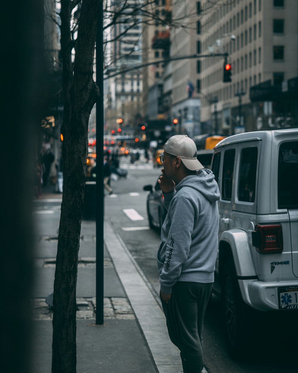 a man standing on the side of a street talking on a cell phone