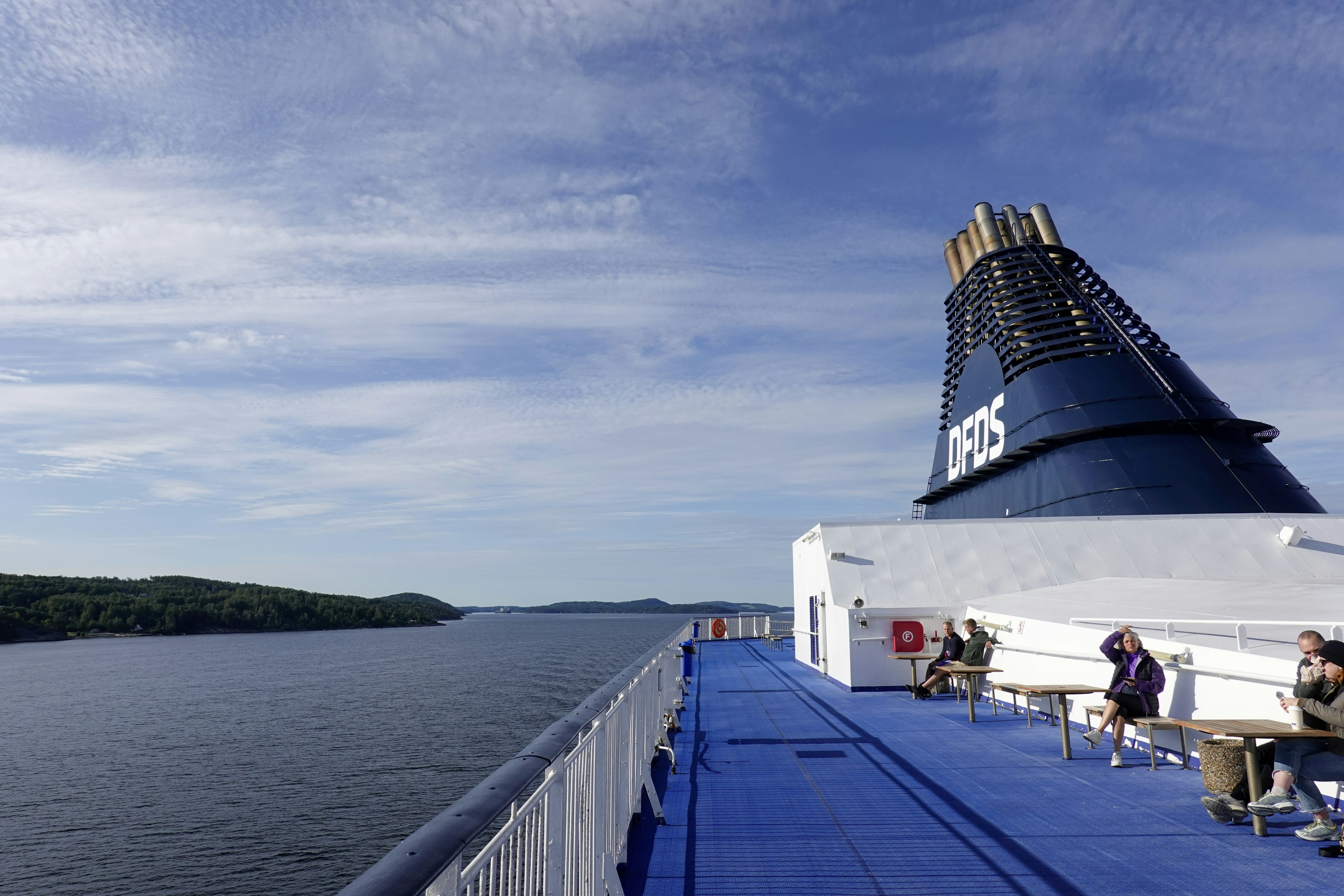 people sitting on benches on the deck of a cruise ship, 