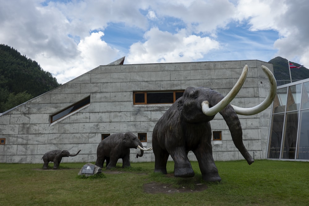 a statue of an elephant and two baby elephants in front of a building
