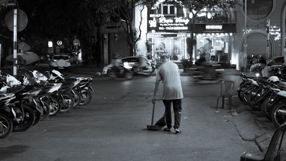 a man with a cane walking down a street next to parked motorcycles