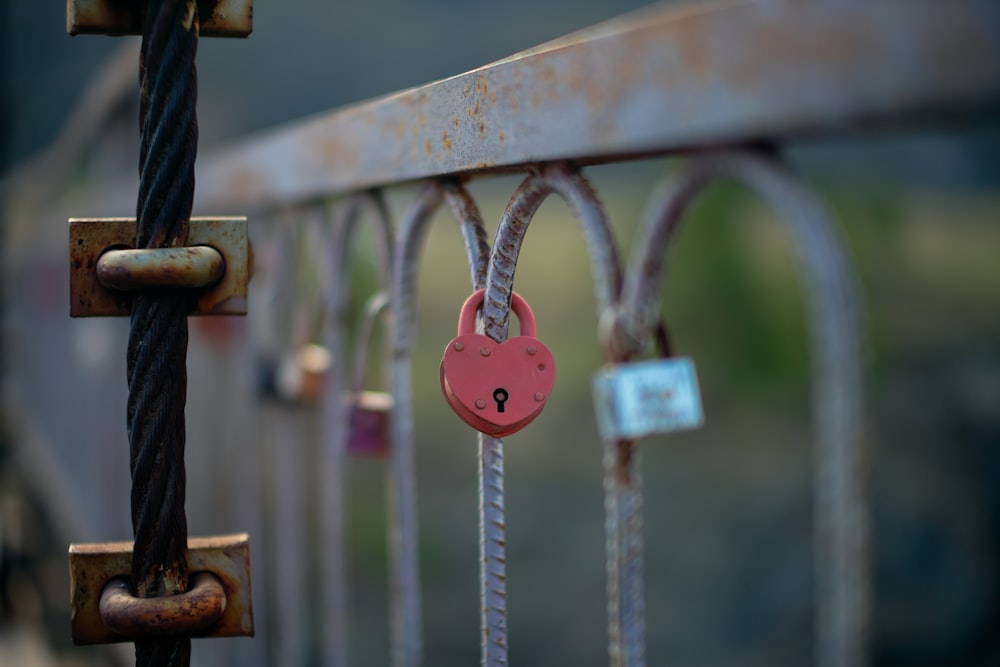 a red padlock attached to a metal fence