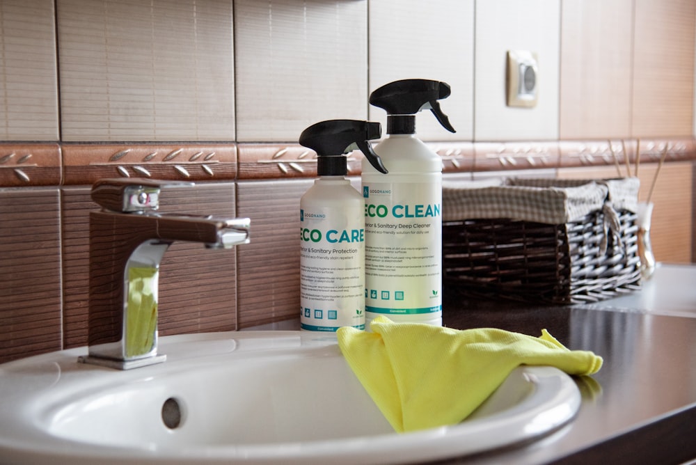 a bathroom sink with two cleaning products on it