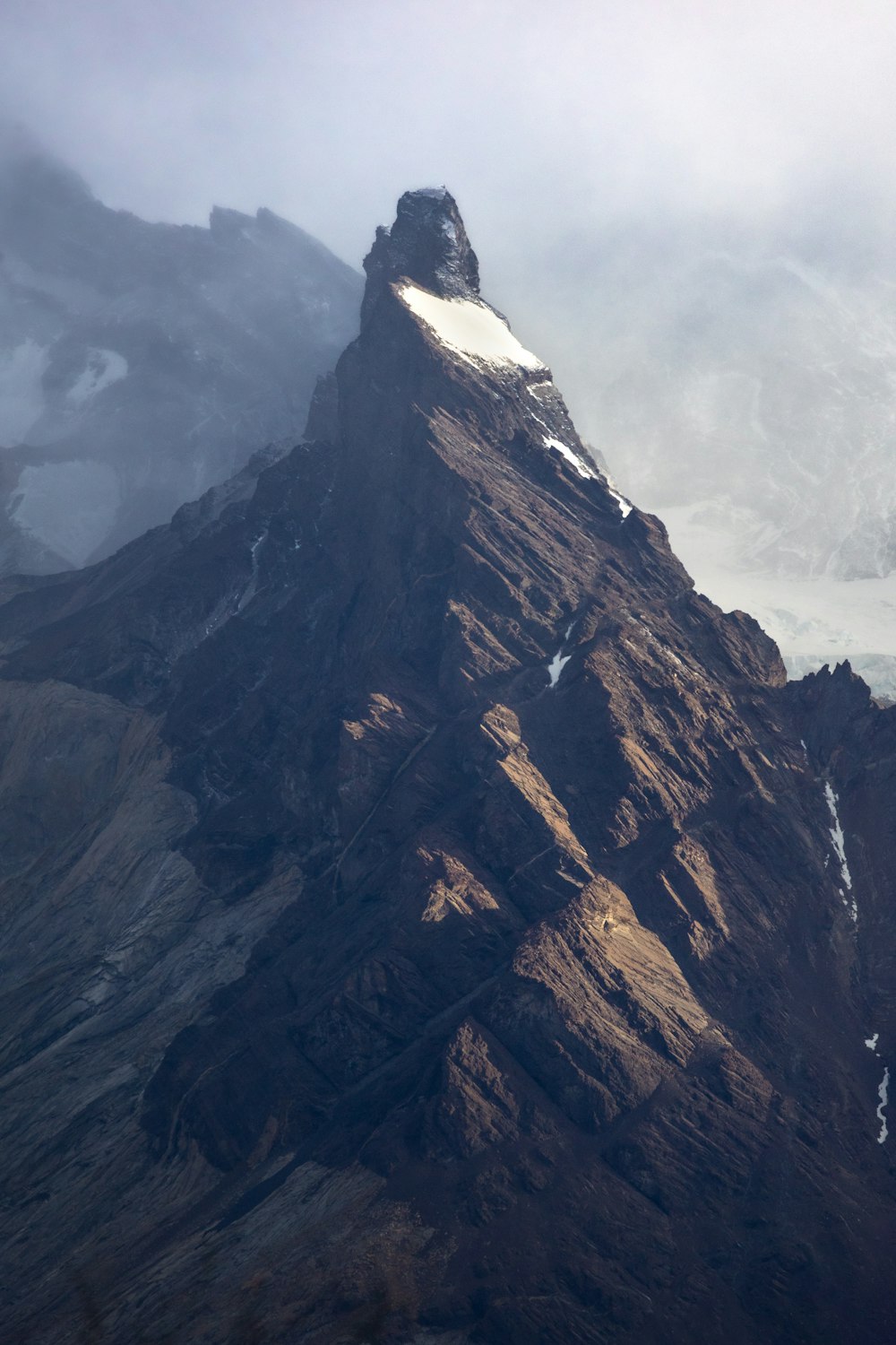 a very tall mountain covered in snow and clouds