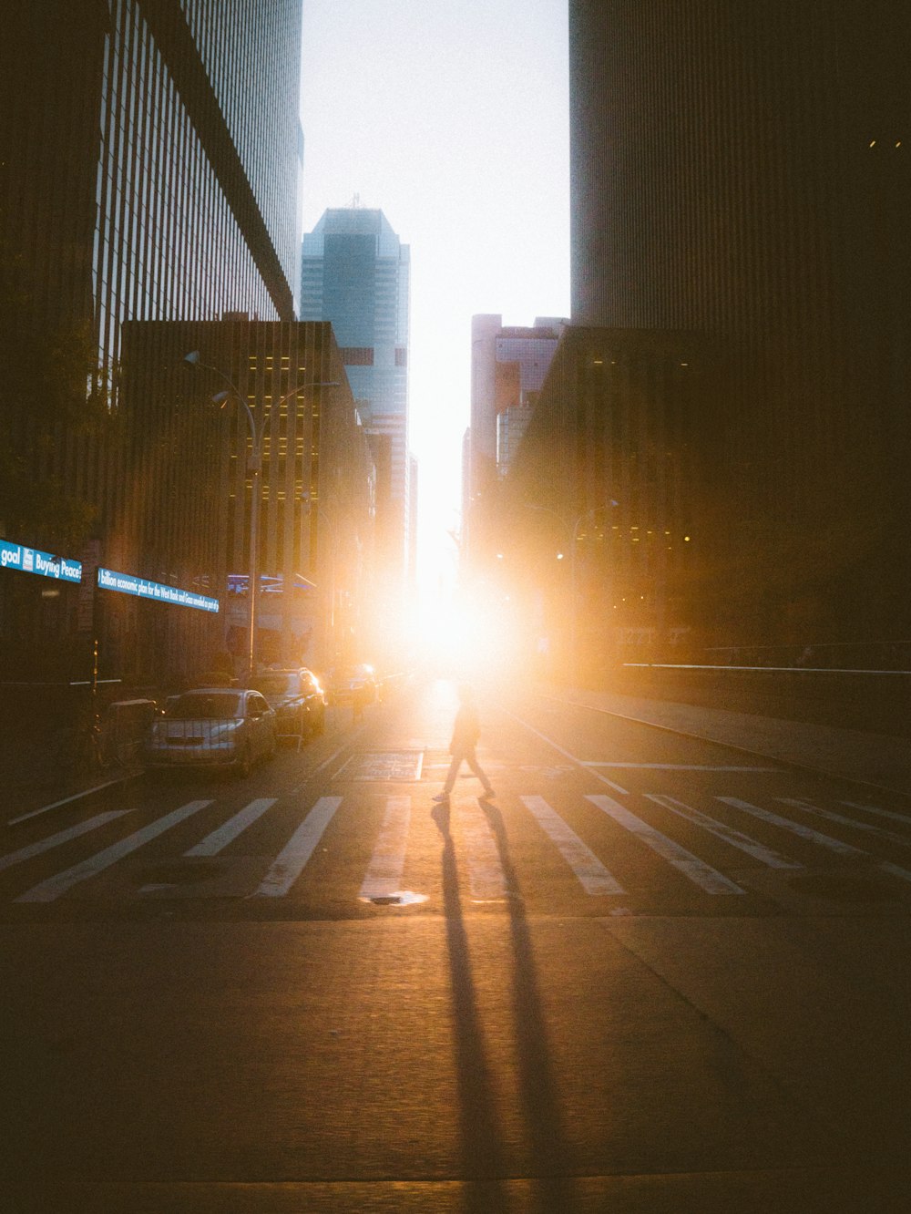 a person walking across a street at sunset