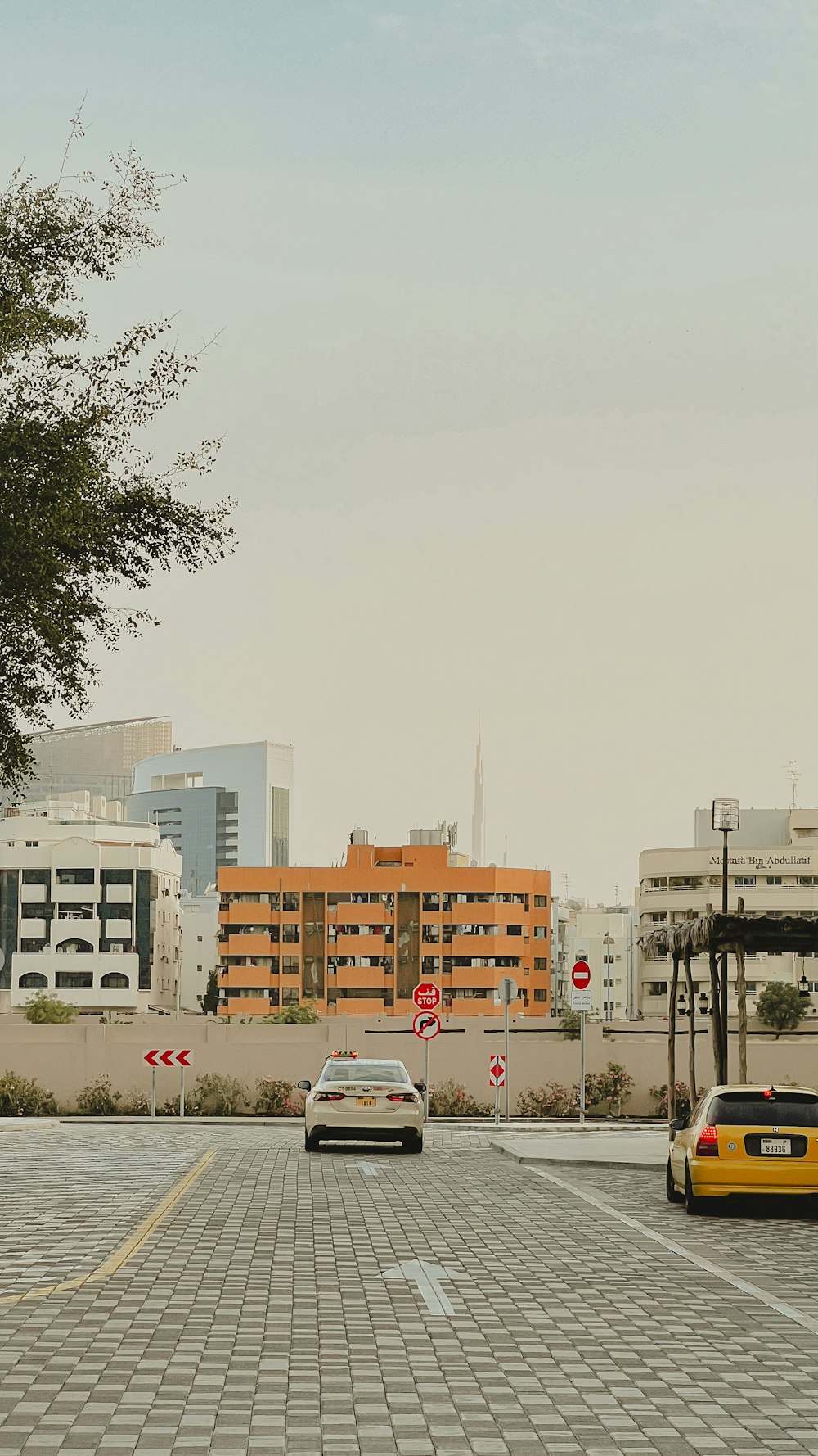 a yellow car driving down a street next to tall buildings