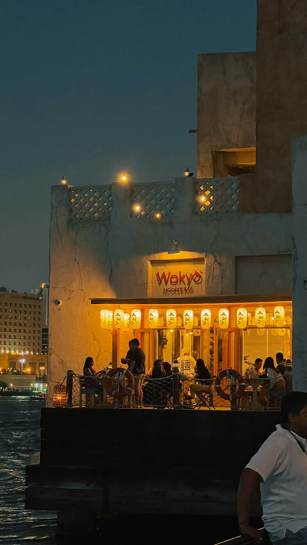 a group of people sitting outside of a restaurant at night