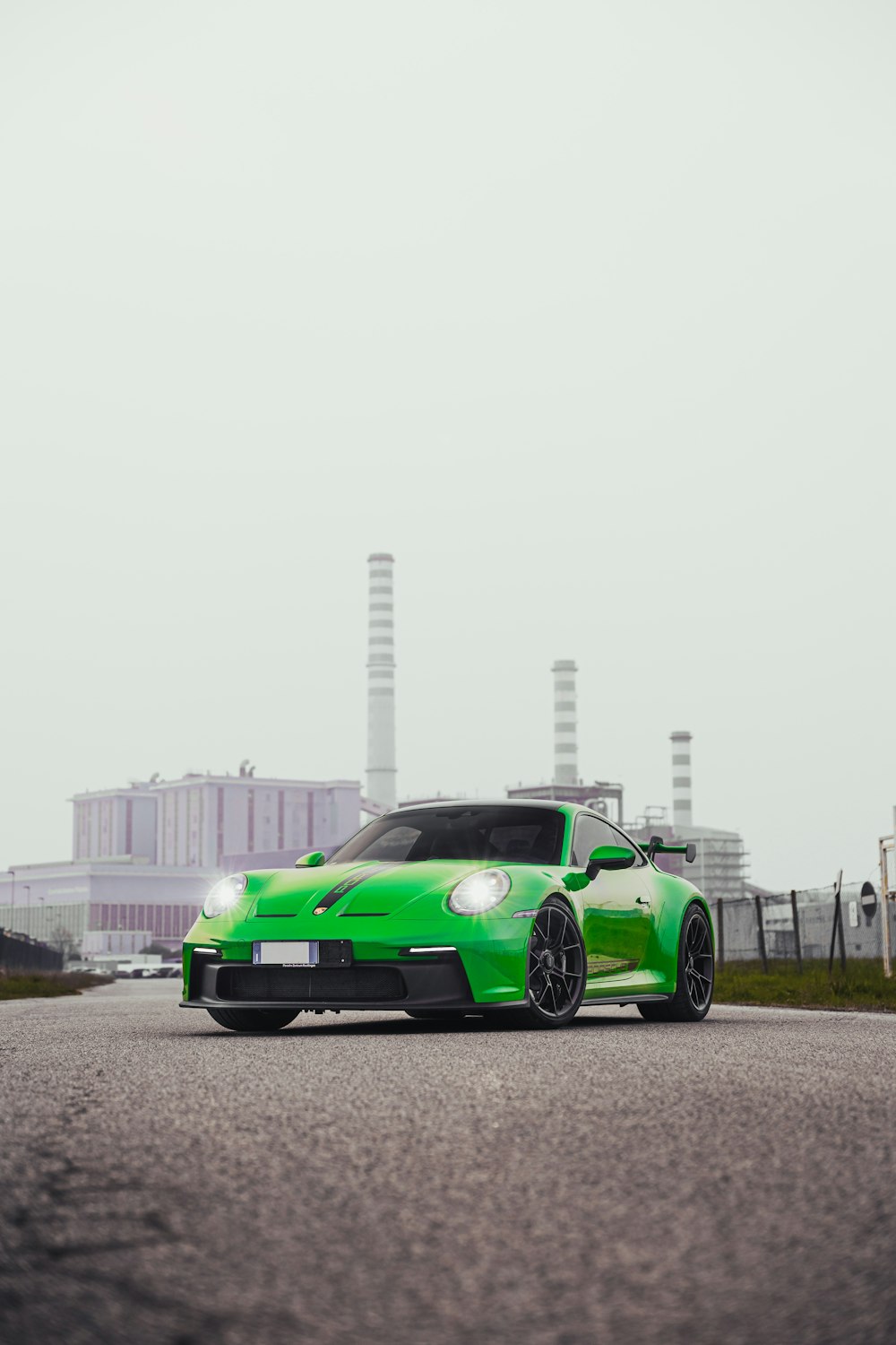 a green sports car parked in front of a factory