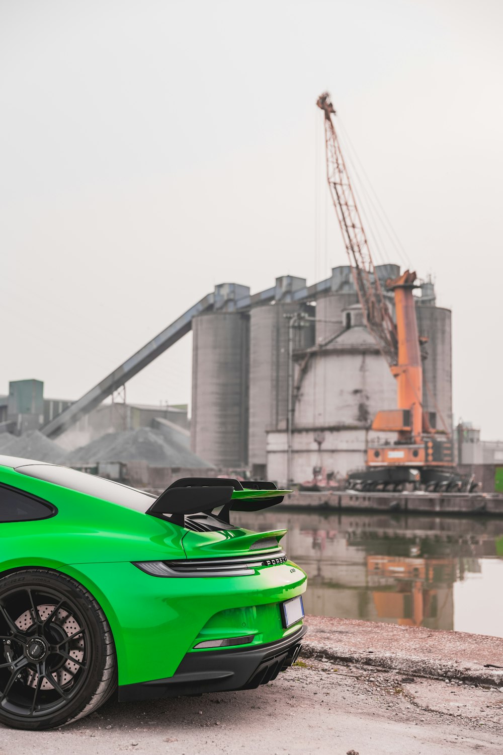 a bright green sports car parked in front of a factory