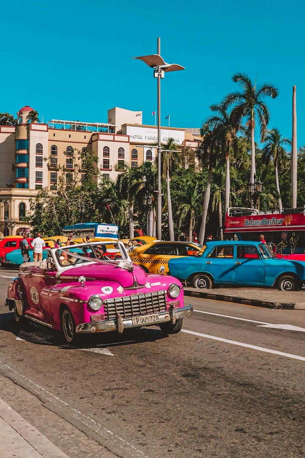 a pink car driving down a street next to tall buildings