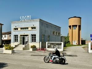 a person riding a motorcycle in front of a building